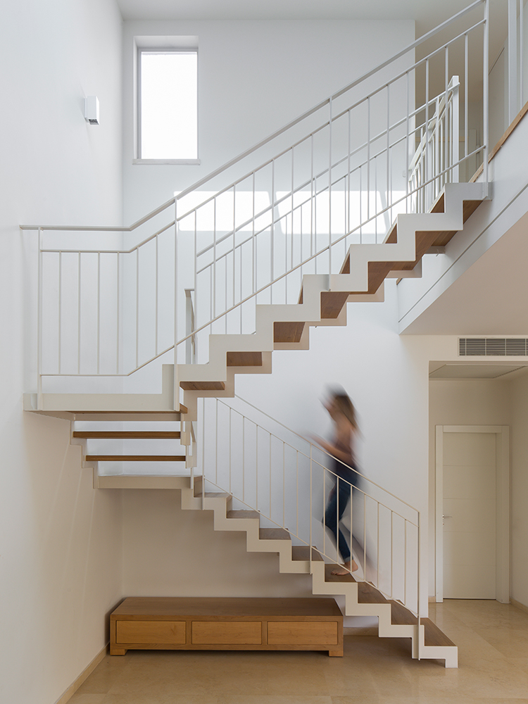 מדרגות מדורגות עם מעקה מתכת לבן בוילה בגבעתיים. הלקוחה אמנית והיתה שותפה בעיצוב ובתכנון המדרגות,למראה עדין קליל ואורירי.